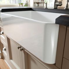 a large white kitchen sink sitting on top of a wooden counter next to a window