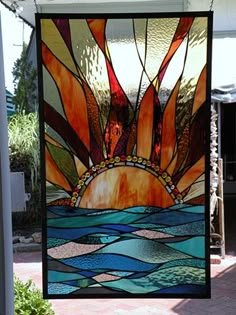 a large stained glass window hanging from the side of a building with an ocean scene on it