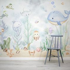 an ocean scene with dolphins, fish and other marine creatures painted on the wall behind a chair