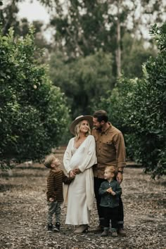 a man, woman and two children standing in an orchard