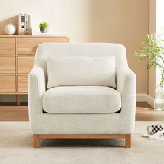 a white chair sitting on top of a rug in a living room next to a dresser