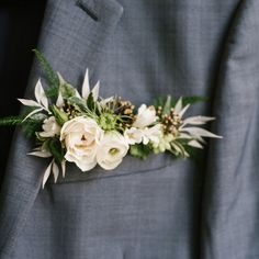 a boutonniere with white flowers and greenery is worn on a man's suit