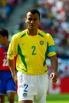 a soccer player in yellow and white is on the field with other players behind him