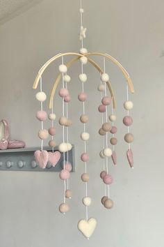 a pink and white mobile with hearts hanging from it's sides in a room