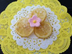 a yellow doily with two slices of lemon on it and a flower in the middle