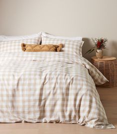 a white and brown checkered comforter on a bed next to a wicker basket