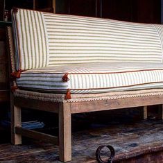 an old wooden couch with striped fabric on it's back and legs, sitting in a room