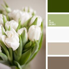 a vase filled with white tulips sitting on top of a table