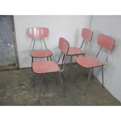 three pink chairs sitting next to each other in a room with white walls and concrete flooring