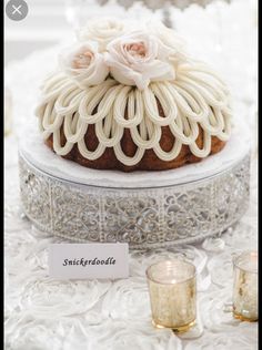 a cake with white frosting and flowers on it sitting on a table next to candles