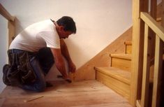 a man kneeling down on the floor with tools in his hand and working on some wood