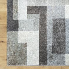 an area rug with different colored squares on the floor in front of a wooden floor