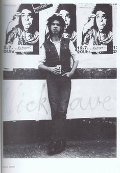 a man standing in front of a wall with pictures on it and his arms crossed