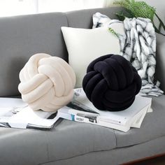 two pillows sitting on top of a gray couch next to books and pillowcases