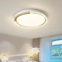 a white bed sitting under a round light in a bedroom