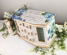 a decorative box sitting on top of a table next to flowers and a figurine