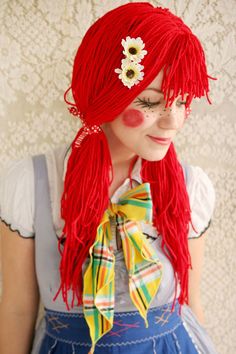 a woman with long red hair wearing a blue dress and yellow flower in her hair