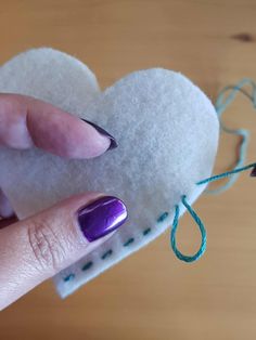 a woman's hand holding a heart shaped piece of felt