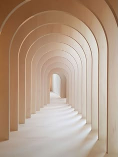 an arched hallway is lined with columns and white walls, leading into the light at the end