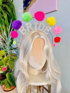 a white wig wearing a bridal tiara with pom - poms on it