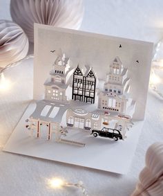 a white card with black and white paper cut out of it's houses, cars and trees