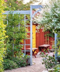 an outdoor garden with wooden benches and plants around it, surrounded by red shipping containers