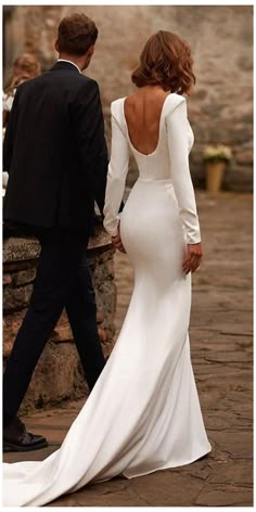 a woman in a white dress walking next to a man in a black tuxedo