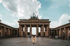 a woman standing in front of a stone arch with statues on it's sides