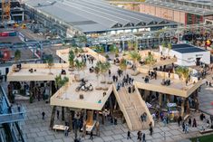 an aerial view of people walking and sitting in front of some buildings with trees on top