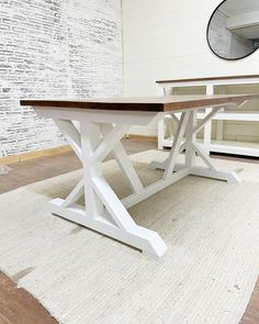 a white table sitting on top of a rug next to a brick wall in a room