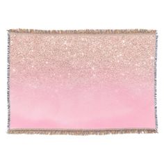 a pink and gold throw blanket with fringes on the edges, against a white background