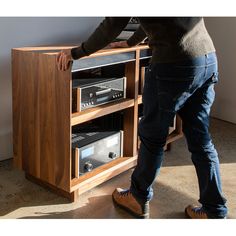 a man standing in front of a wooden cabinet with two stereos on top of it