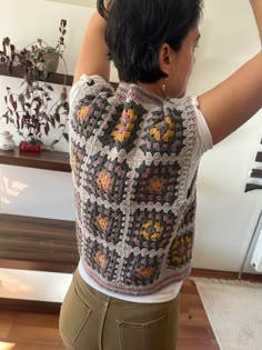 a woman is wearing a crocheted vest with flowers on it