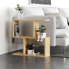 a white couch sitting next to a wooden shelf with potted plants on top of it