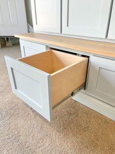 an open drawer in the middle of a kitchen countertop with white cabinets and drawers