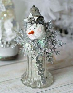 a glass snowman with a hat and scarf on it's head sitting in a vase