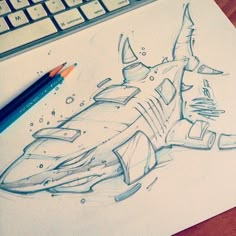 a pencil drawing of a shark on top of a piece of paper next to a keyboard