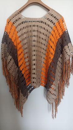 an orange and brown crocheted sweater hanging on a hanger