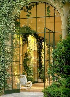 an arch covered in vines with a white chair