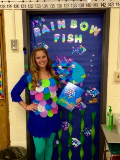 a woman is standing in front of a door decorated with fish and bubbles, holding a book