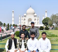 four men are sitting on a bench in front of the taj - ihan