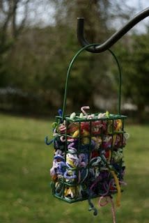 a bird feeder filled with lots of colorful yarn