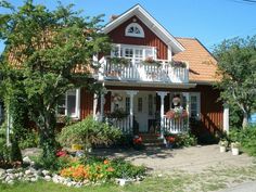 a red and white house with flowers in the front yard