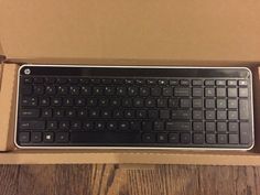 a keyboard in a cardboard box on a wooden table with it's lid open