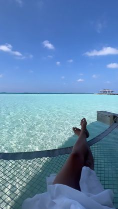 a person laying down on a hammock in the ocean with their feet up