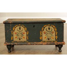 an old wooden box with decorative designs painted on it's sides sitting on a wood floor