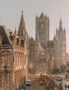 cars are parked on the street in front of large buildings with spires and steeples