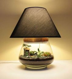 a lamp that is on top of a table with some plants in the bowl underneath it