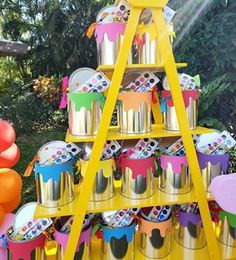 there is a yellow stand with cups on it and balloons in the air next to it