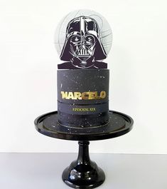 a darth vader cake on top of a black plate with a star wars logo